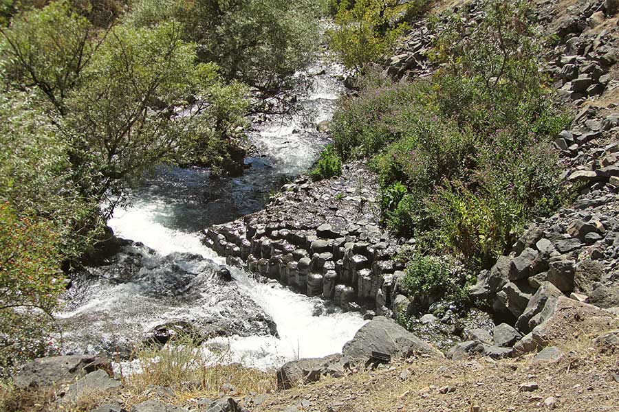 Ein wilder Bergbach fließt über Basaltstelen