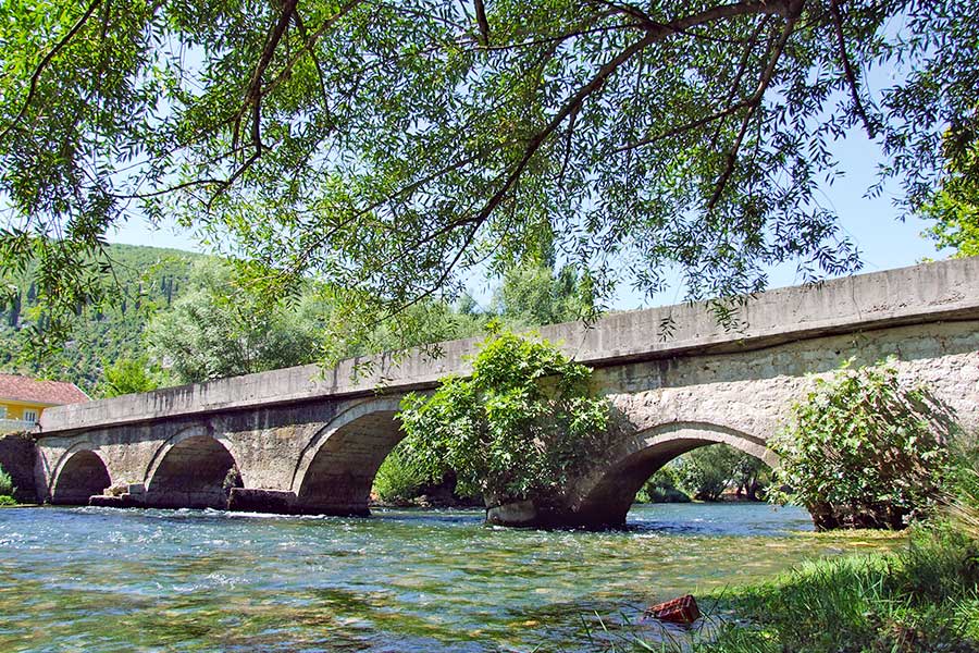 Eine alte Bogenbrücke aus Stein über einem klaren Fluss