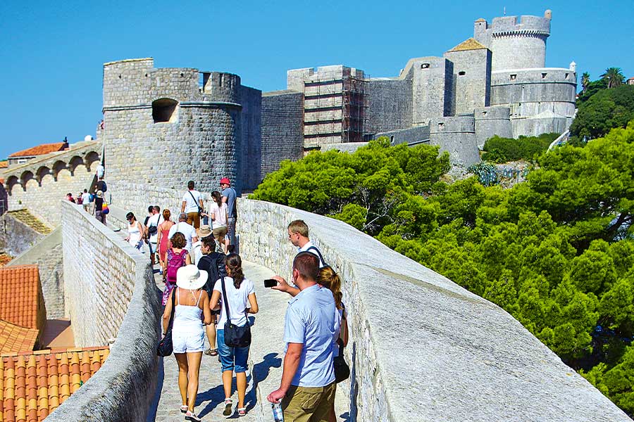 Touristen auf einer Stadtmauer, die zur Burg führt
