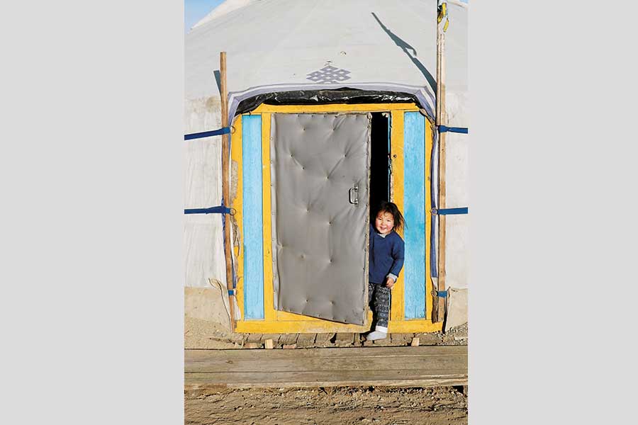 Ein lachendes Kind schaut aus einer Jurtentür