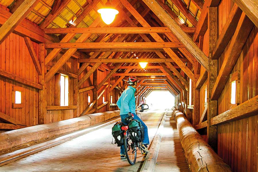 Radfahrerein steht auf einer überdachten Holzbrücke