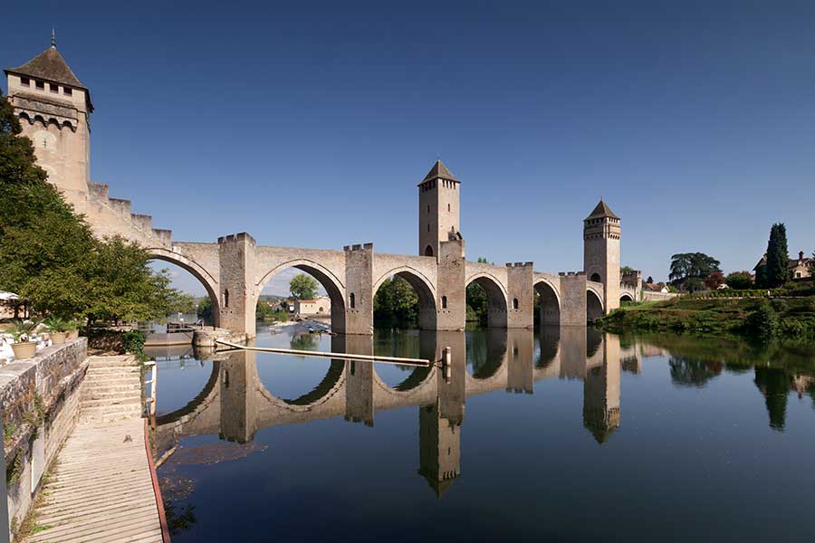Die Bogenbrücke Pont Valentré in Cahors spiegel sich im Fluss Lot in Südwestfrankreich